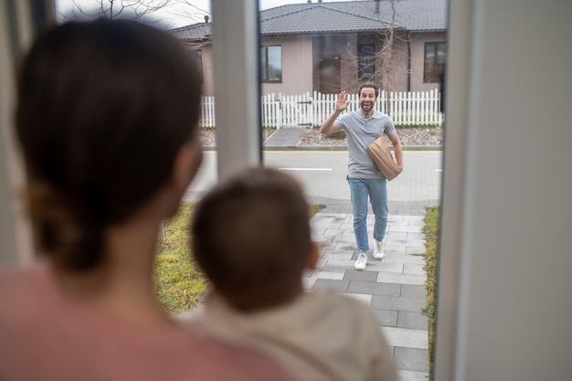 Esposa e hijo esperando al hombre que regresa a casa de la compra de alimentos