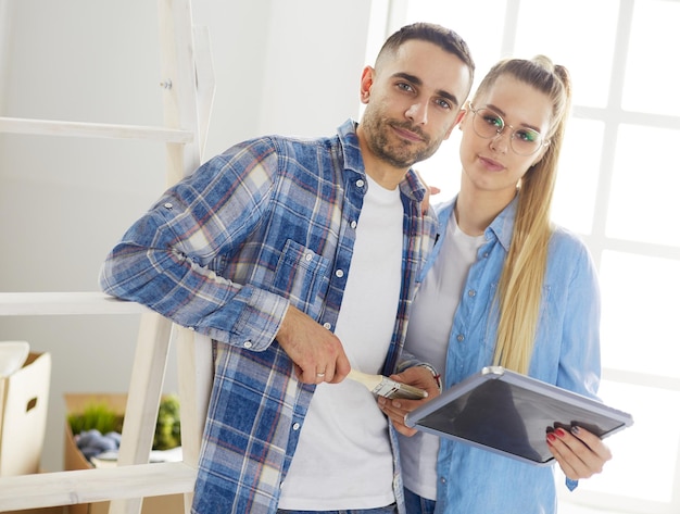 Esposa e marido sorridentes em pé na sala de estar e discutindo o interior do apartamento se mudando para uma nova casa