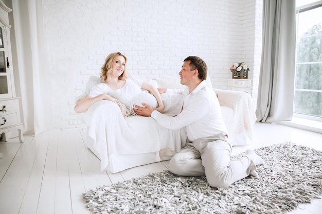 Esposa embarazada y su amado esposo en la sala de estar. el concepto de felicidad familiar
