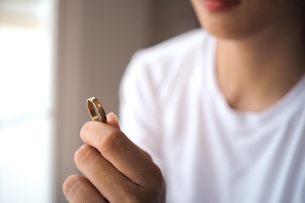 La esposa está triste y deprimida después del divorcio sosteniendo con la mano un anillo de bodas