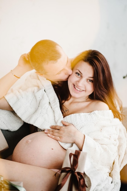 Esposa grávida e marido coberto com manta em casa Pessoas de férias de gravidez e conceito de expectativa