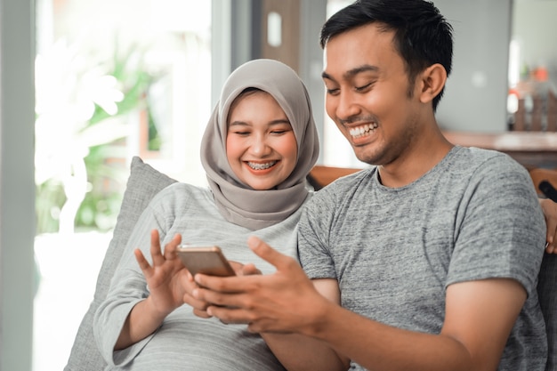 Esposa grávida e marido usando smartphone