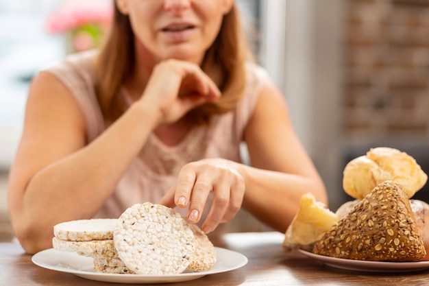 Esposa loira com forte alergia comendo batatas fritas sem glúten em vez de pão