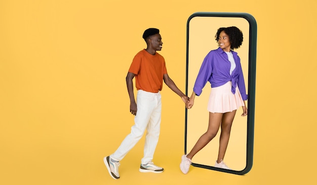 Esposa negra milenar positiva em mão de homem casual leva a um grande smartphone, aproveite o encontro e grátis