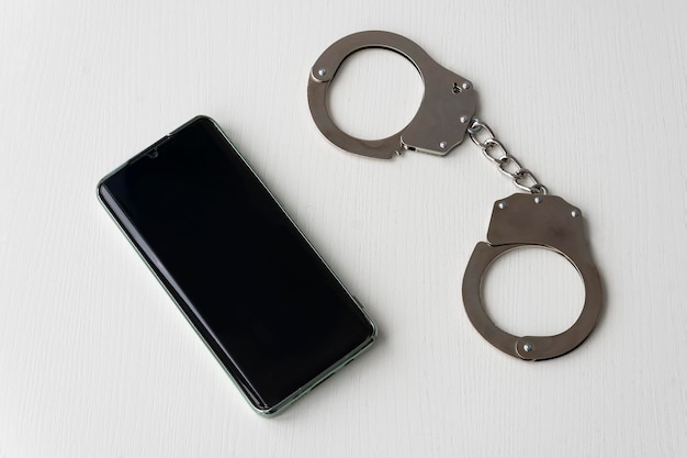 Esposas y teléfono móvil en el primer plano de la mesa de madera derecho a llamar cuando es arrestado o detenido por la policía