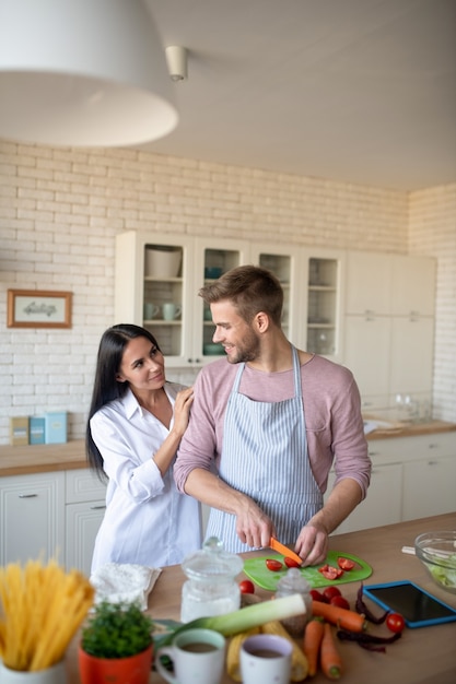 Esposo cocinando esposa vistiendo camisa blanca llegando al esposo cocinando en la mañana