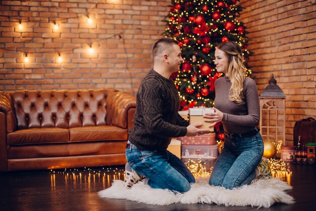 El esposo le da a su esposa un regalo de Navidad en casa