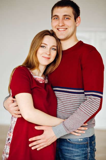 El esposo y la esposa, amantes vestidos con un estilo borgoña. Pareja joven y atractiva: madre embarazada y padre feliz