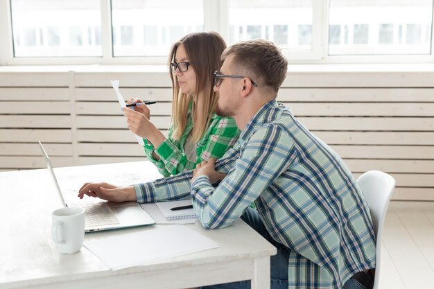 El esposo y la esposa concentrados cuentan las compras y facturas del último mes y registran los resultados en la contabilidad de su casa en un cuaderno y en una computadora portátil. Concepto de ahorro y contabilidad.