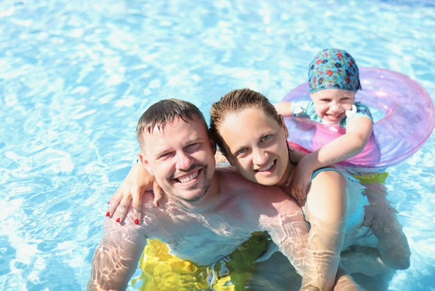 Esposo con esposa e hijo nadan juntos en la piscina