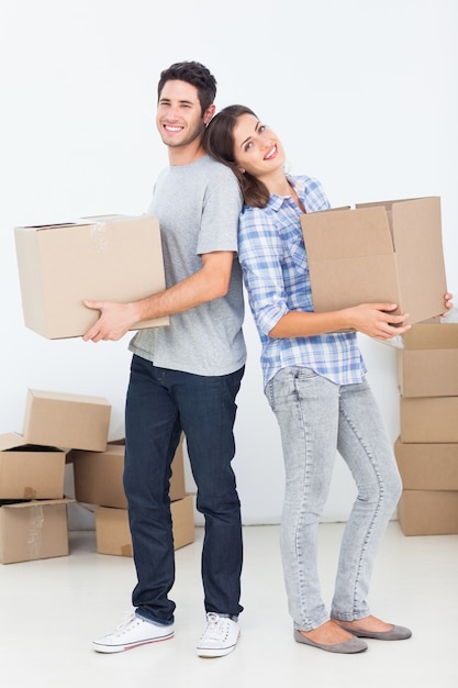 Esposo y esposa llevando cajas en su nueva casa