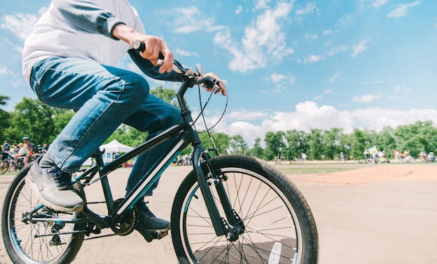 El esposo de Hipster monta una bicicleta en un clima soleado de verano. Caminando en el parque en bicicleta. Bicicleta de primer plano