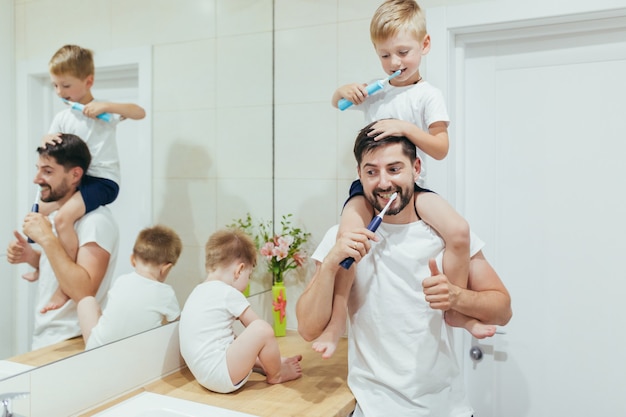 esposo papá enseña niño pequeño cepillarse los dientes