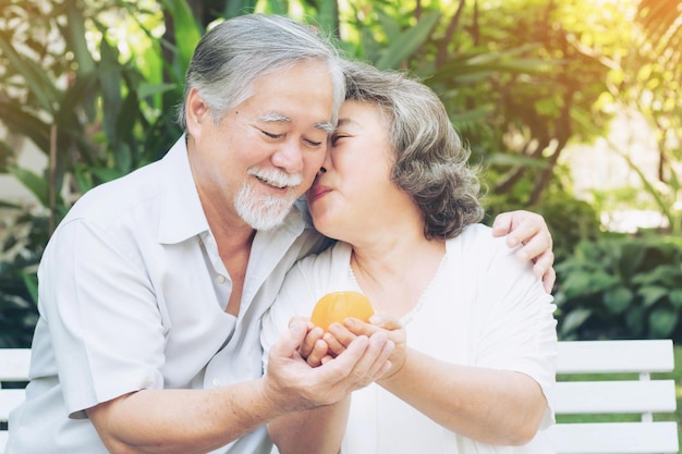 El esposo de una pareja de ancianos jubilados entregando fruta y luego su esposa lo besó en la mejilla expresando amor y gratitud en el jardín en el estilo de vida de la casa concepto saludable de pareja de amor para personas mayores