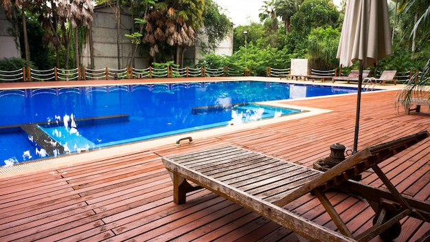 Foto espreguiçadeira de madeira com guarda-chuva na piscina moderna