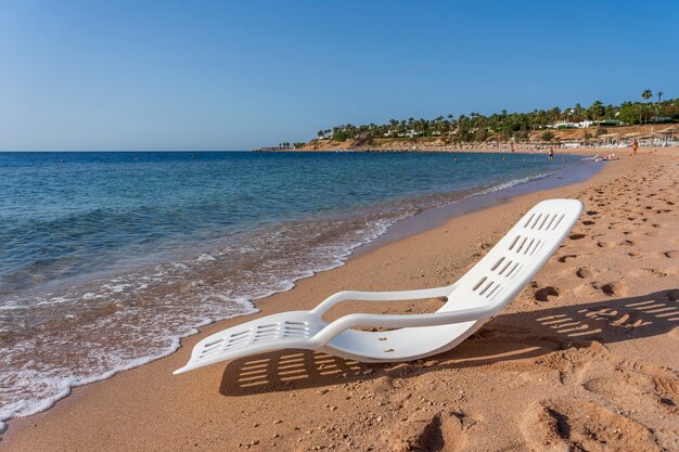 Espreguiçadeira de plástico branco perto da água do mar em uma praia tropical em Sharm El Sheikh, Egito. Conceito de viagens e natureza