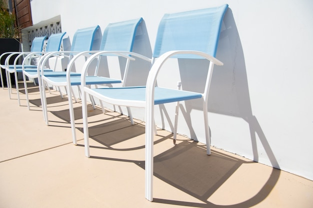 Espreguiçadeiras ao ar livre. Cadeiras de pátio azul na parede ensolarada. Móveis de pátio ou piscina para lazer. Espreguiçadeiras no quintal ensolarado.