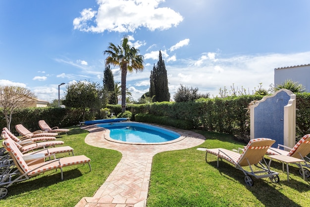 Espreguiçadeiras e colchões perto da luxuosa piscina para relaxar.