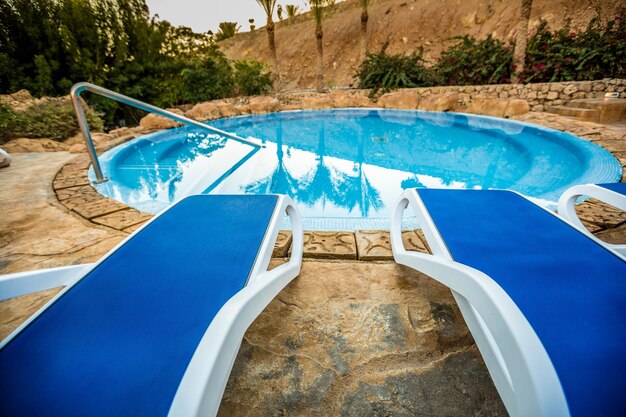 Espreguiçadeiras e piscina com palmas refletidas na água