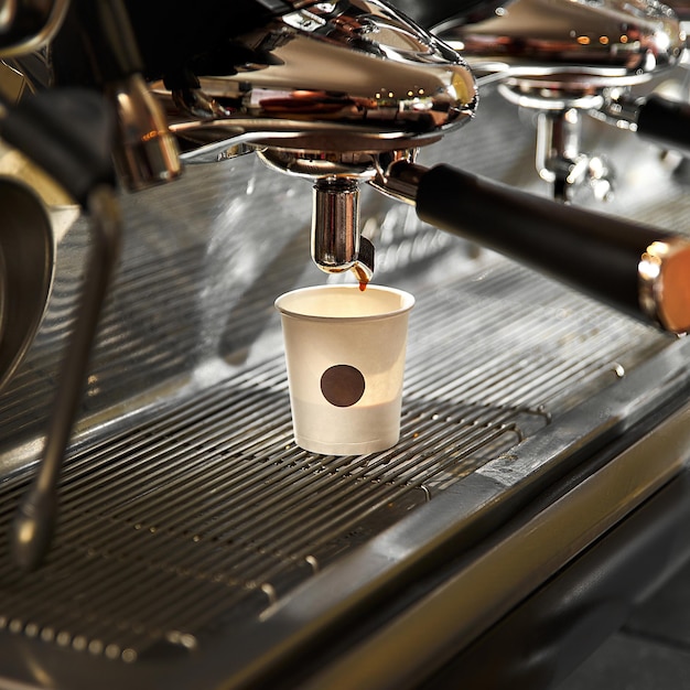 Espresso derramando da máquina de café em xícara de papel descartável de café Cena real em bar