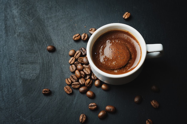 Espresso humeante sabroso en taza con granos de café.