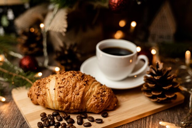 Espresso-Kaffee-Croissant in der Nähe des Weihnachtsbaums auf dem Tisch Kaffeepause