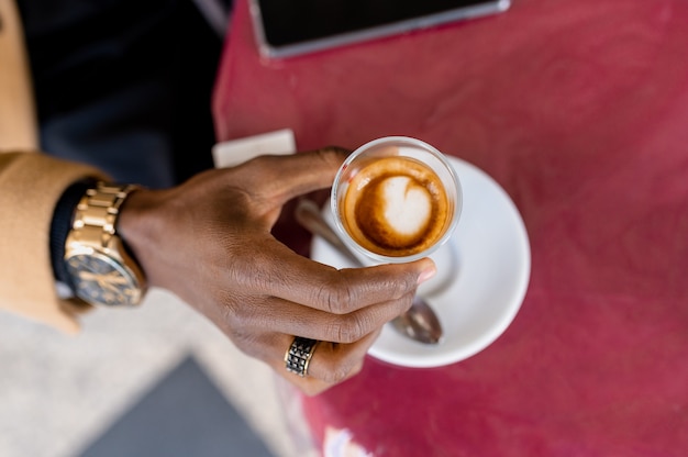 Espresso-Kaffee von oben. Nicht erkennbarer schwarzer Mann mit Tasse.