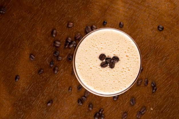 Espresso martini coquetel em copo servido sob suporte de borracha com grãos de café derramados na mesa