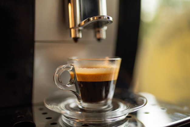 Foto espresso-maschine zu hause - kaffeegetränk in glasbecher bereit in einer minute für geschmacksliebhaber