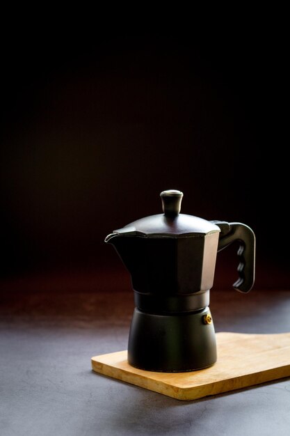 Foto espresso o café negro y olla de moka en una tabla de cortar de madera y una mesa oscura