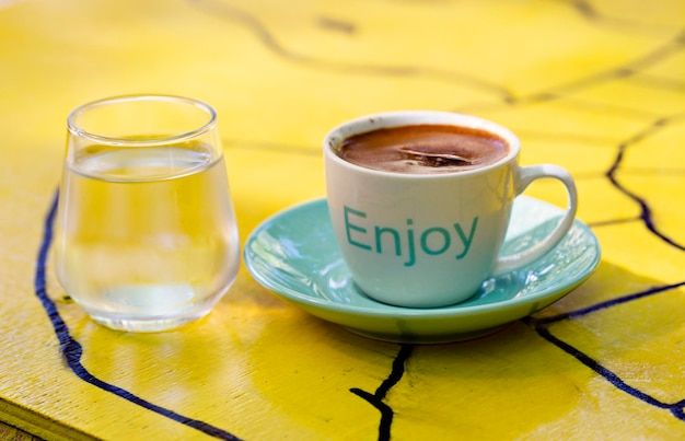 Espressokaffee in einer kleinen Tasse mit dem Wort „Genießen“ darauf geschrieben