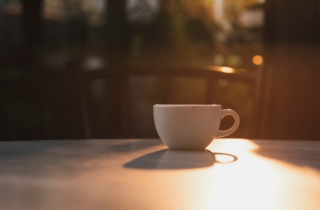 Espressokaffeetasse auf Tabellencafé und Sonnenlicht morgens.