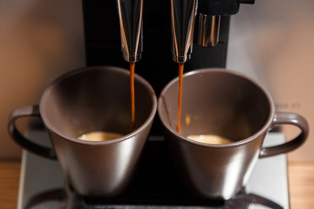 Espressomaschine gießt Kaffee in zwei Tassen