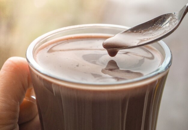 Espuma de café negro en una cucharadita. Una taza de café.