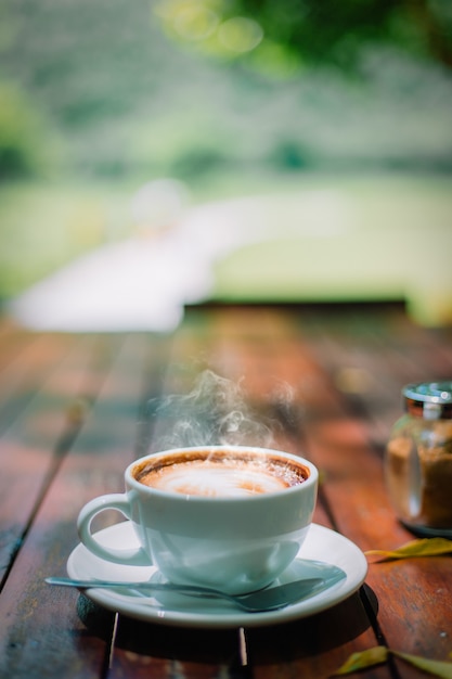 Foto espuma caliente del café con leche del capuchino del latte del café en la mesa de madera en cafetería