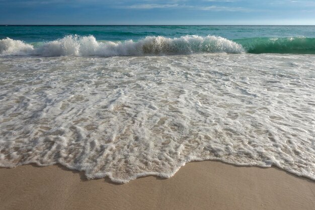 Espuma de onda na praia de areia branca