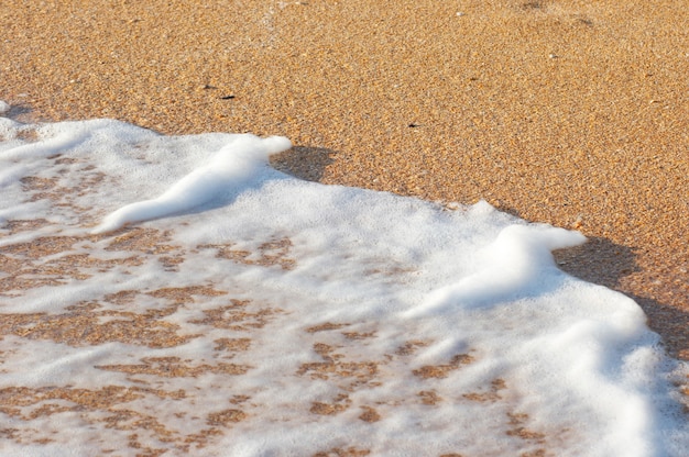 Espuma de surfe na areia da costa