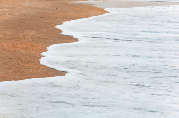 Espuma de surfe na areia da costa