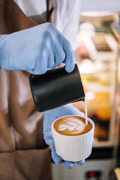 Espuma de leche vertida en una taza para formar un capuchino perfecto