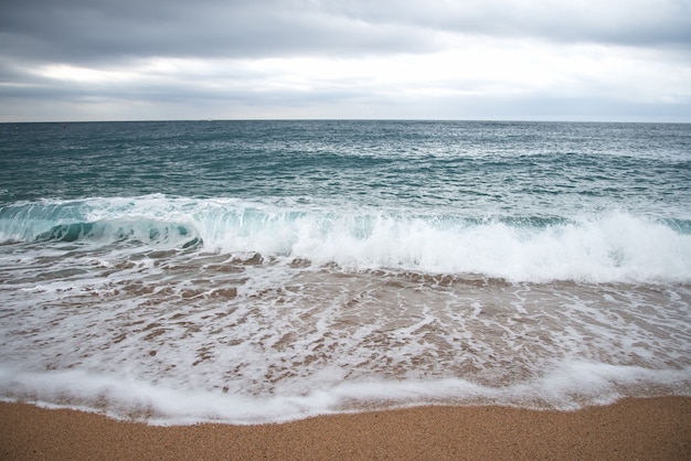 Las espumosas olas del mar ruedan hacia la orilla arenosa