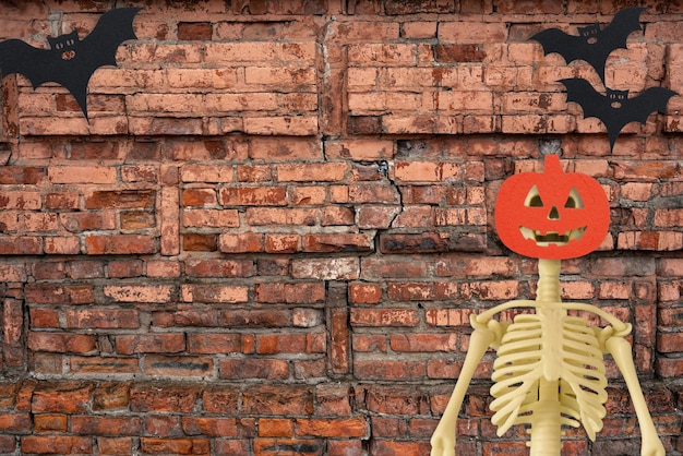 Esqueleto de Halloween e morcego no antigo fundo de tijolos vermelhos