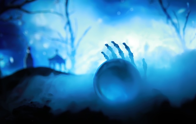 Esqueleto Zombie Mão Saindo De Um Cemitério - Halloween. Previsões de bolas mágicas misteriosas e fumaça na cena escura. Cartomante, poder da mente, conceito de previsão. fundo misterioso