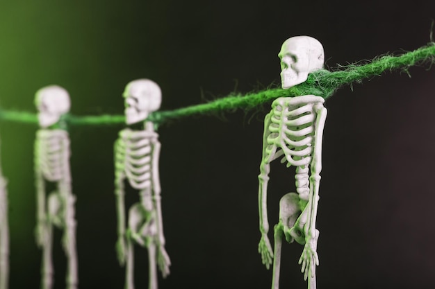 Esqueletos decorativos pendurados em uma corda em um fundo sombrio