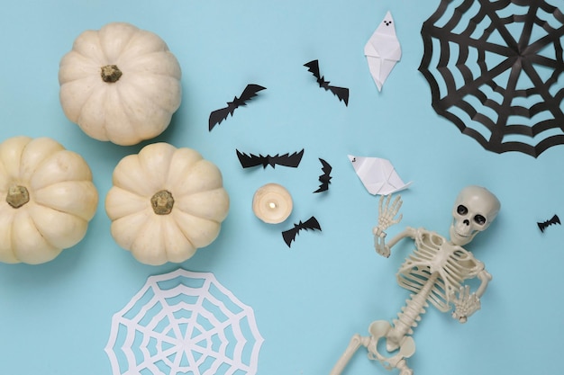 Esqueletos e abóboras de decoração artesanal de Halloween em fundo azul Vista superior plana