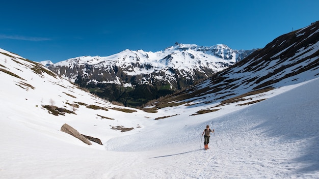 Esqui de caminhada do alpinista que visita na inclinação nevado para a cimeira da montanha. Conceito de conquistar adversidades e alcançar o objetivo.