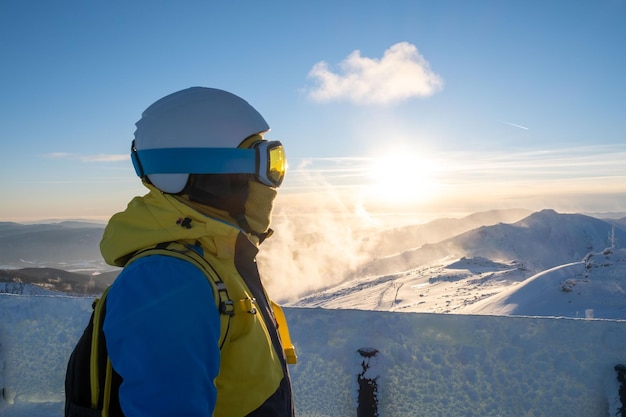 Esquiador de mulher olhando o pôr do sol acima das montanhas da Eslováquia