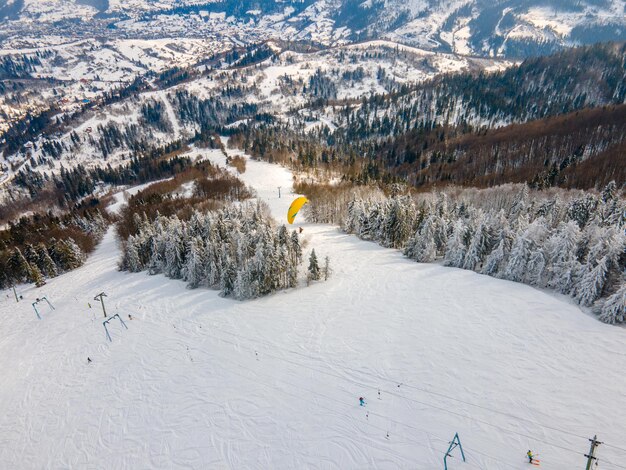 Esquiador de parapente acima da pista de esqui na montanha esporte radical