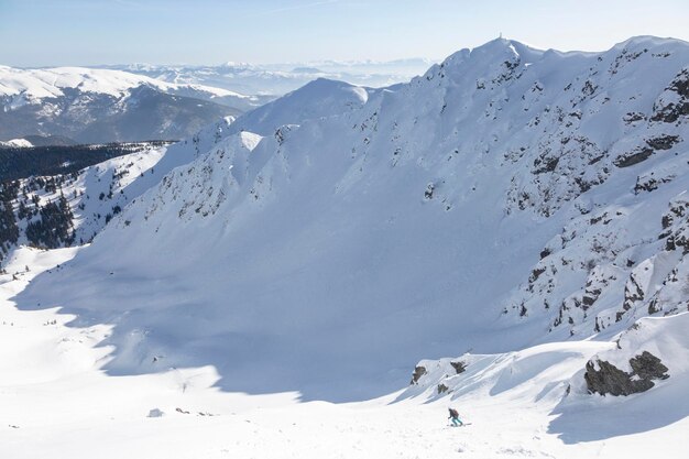 Un esquiador desciende una fuerte pendiente entre rocas y picos nevados