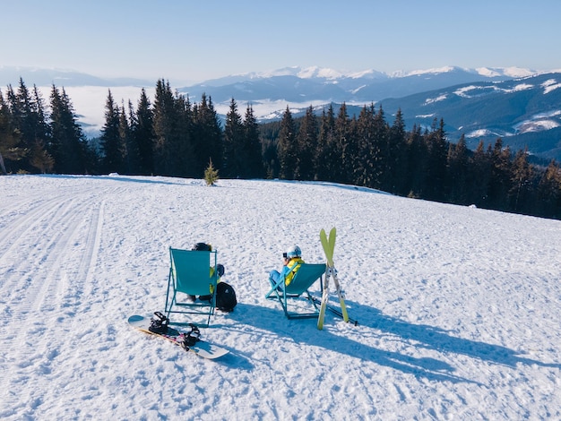 Esquiador e snowboarder sentado no topo das montanhas em cadeiras desfrutando. férias de inverno