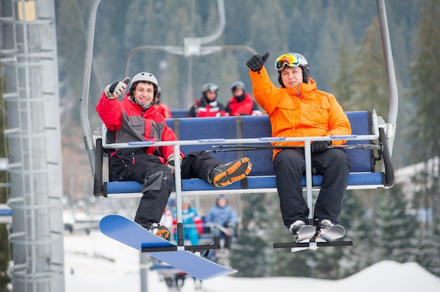 Esquiador e snowboarder subindo no teleférico